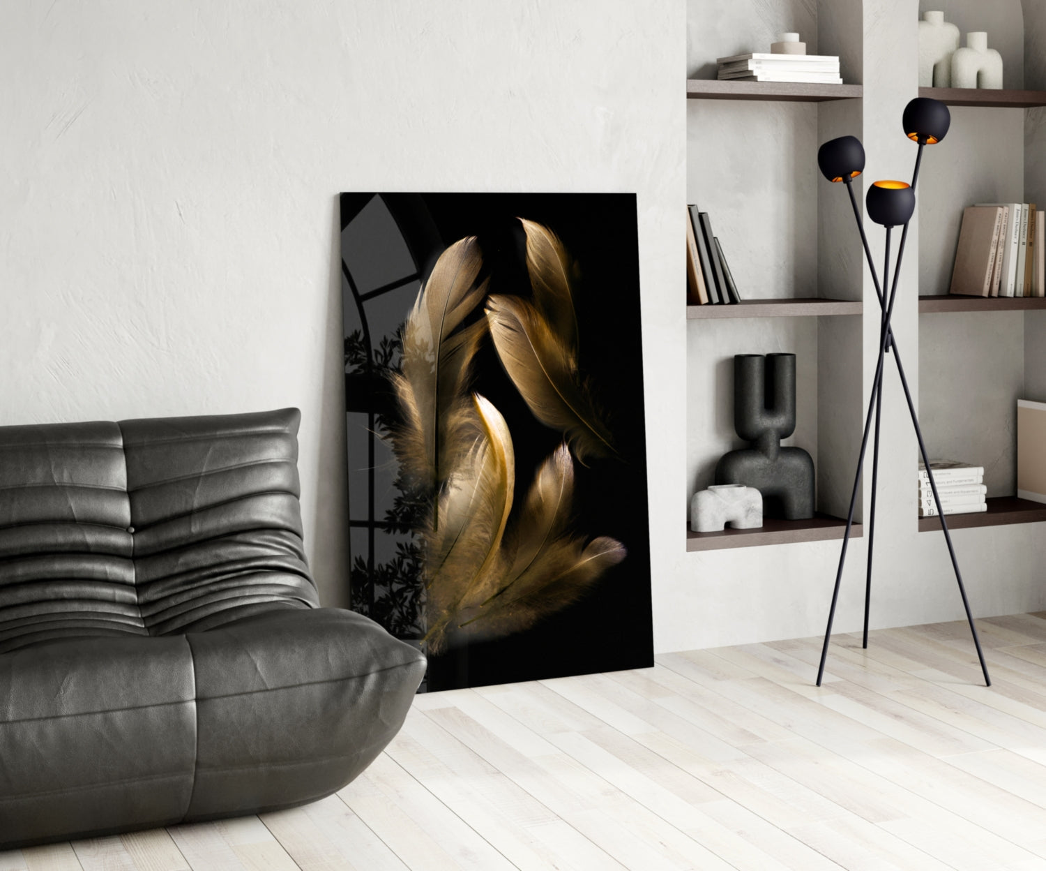 Tan feather glass wall art displayed in a modern living room beside a gray leather chair and black floor lamp with shelving.