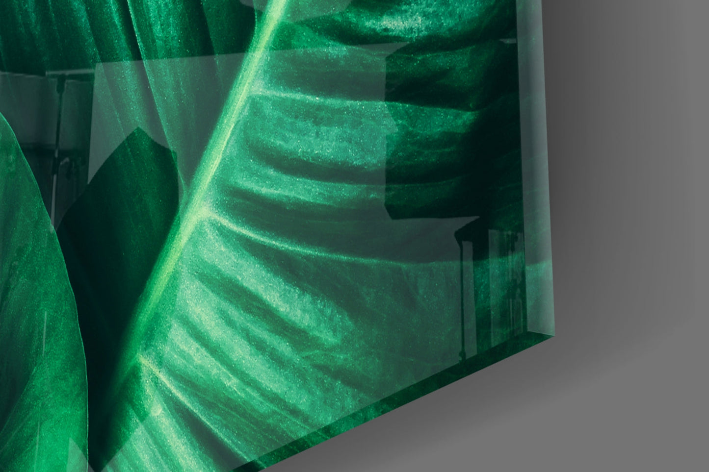 Close-up angled view of layered green glass art with translucent leaf vein details and light reflection.