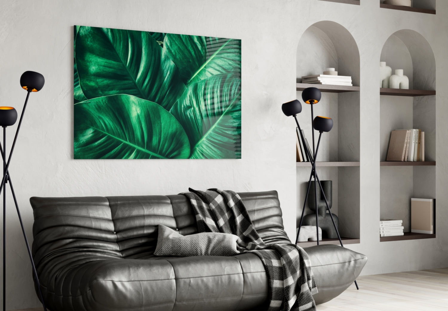Green tropical leaf glass wall art hung above a gray leather sofa in a modern living room interior.