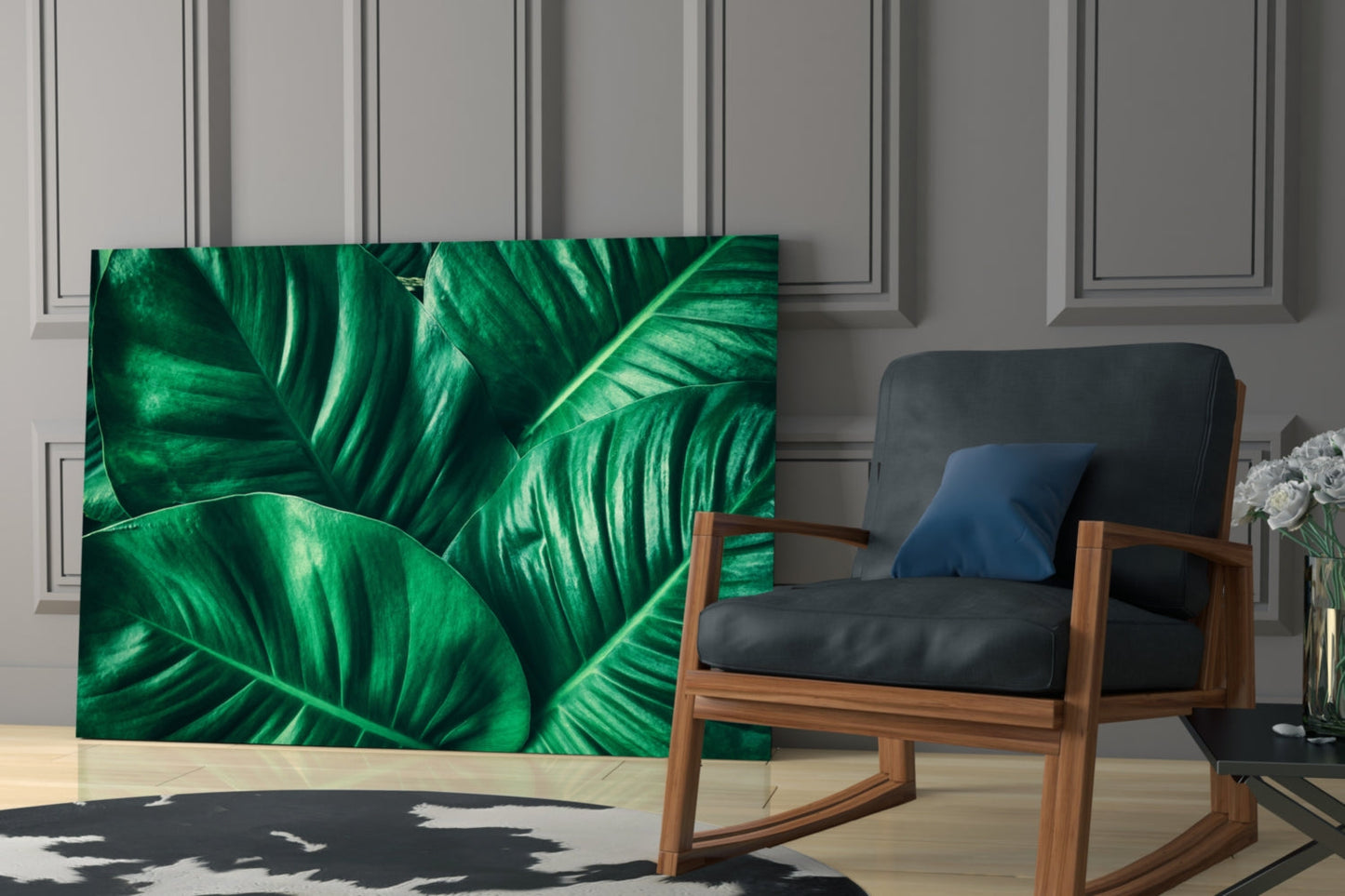 Green tropical leaf glass wall art displayed on a light gray paneled wall next to a wooden chair with black cushions.