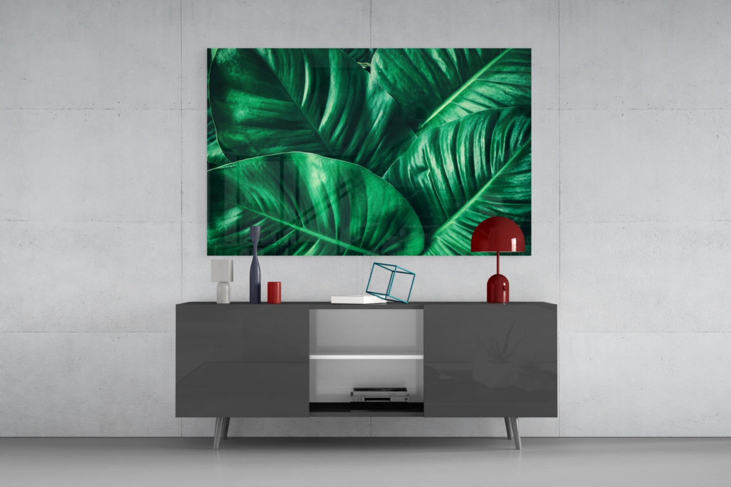 Green tropical leaf glass wall art displaying vibrant foliage mounted above a dark media console in a modern living room setting.