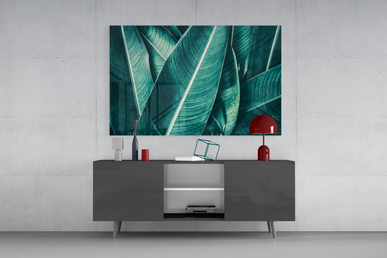 Green tropical leaf glass wall art displaying teal striped leaves mounted above a dark gray media console in a modern living room setting.
