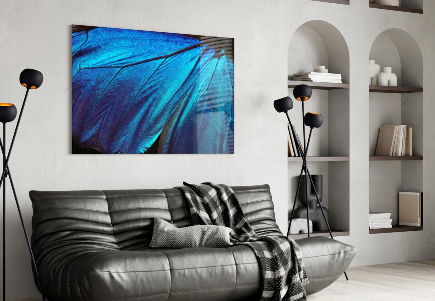 Modern living room with blue butterfly wing glass wall art above black leather sofa, flanked by decorative floor lamp and white shelving.