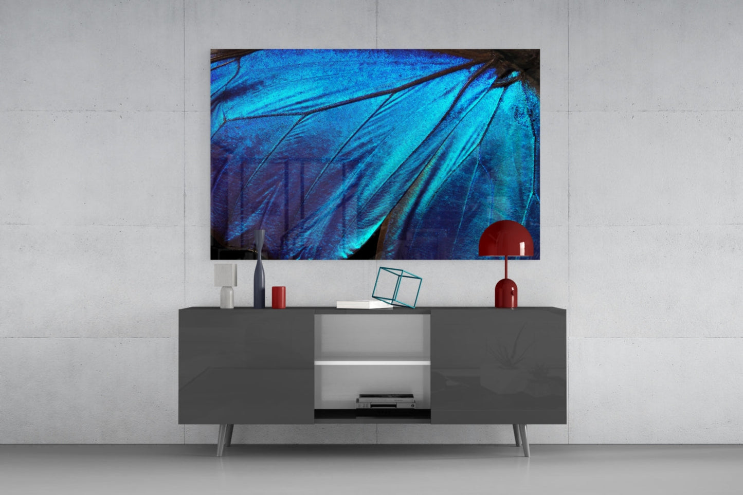 Butterfly wing glass wall art displaying vibrant blue iridescent feather patterns mounted above a gray media console in modern interior setting.