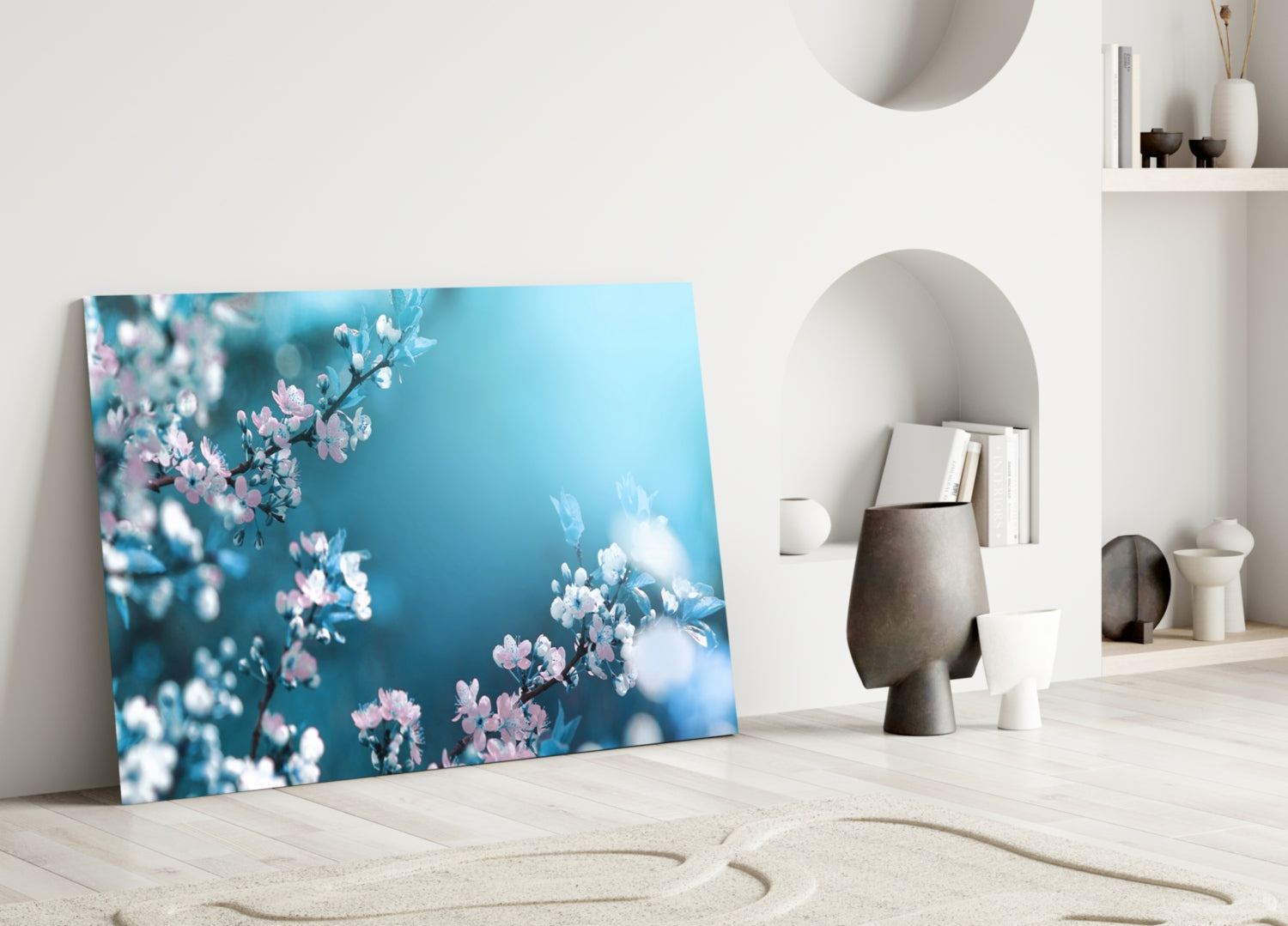 Glass wall art leaning against white wall displays pink and white flowers against turquoise blue background.