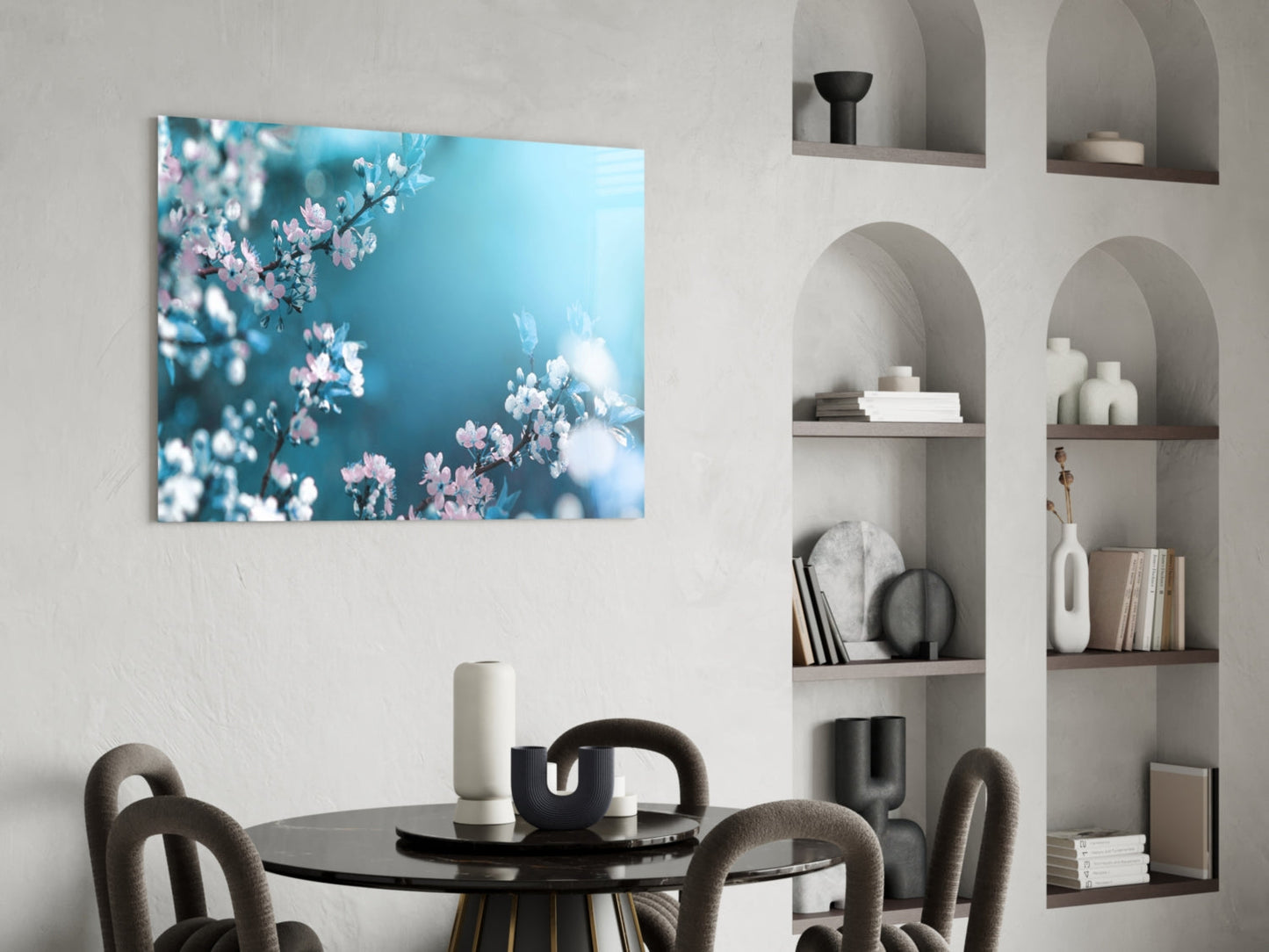 Glass wall art featuring pink and white spring blossoms against a turquoise blue sky, displayed above a black dining table.