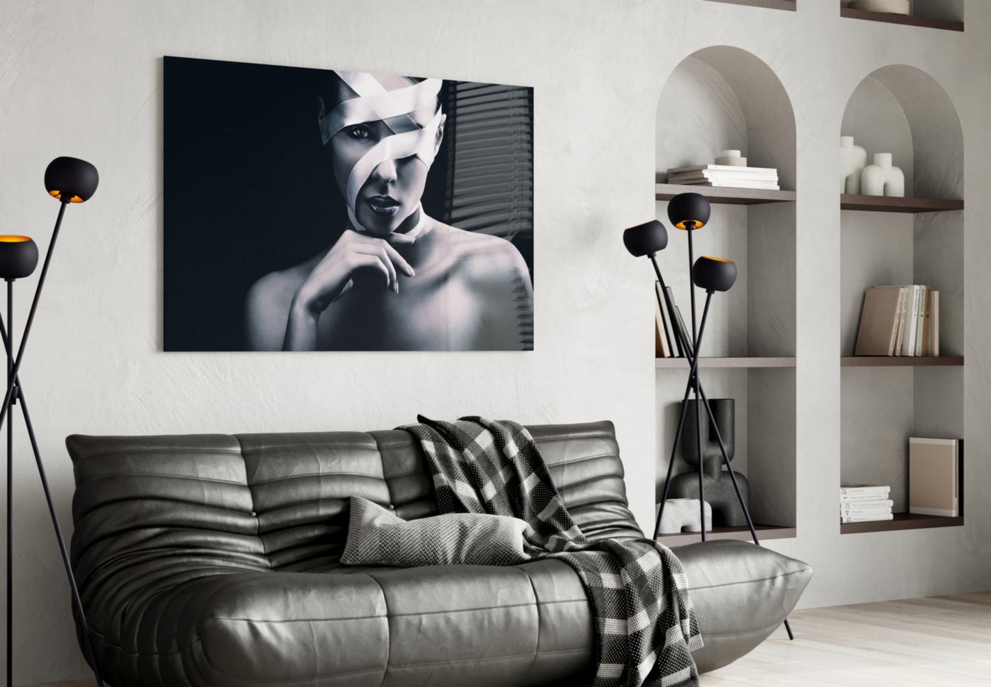 Black and white portrait of a woman with wrapped head displayed above gray leather sofa in modern living room setting.