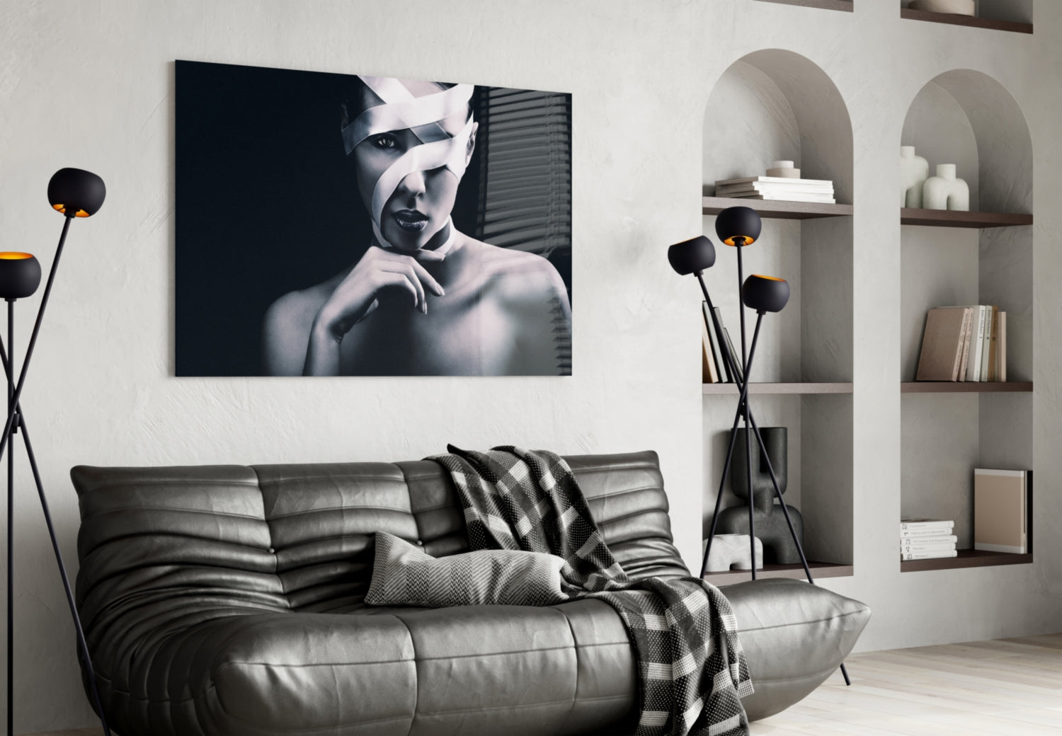 Black and white portrait of a woman with wrapped head displayed above gray leather sofa in modern living room setting.