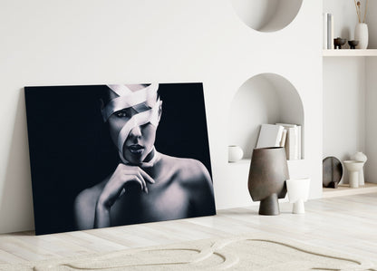 Black and white portrait glass art leaning against white wall in minimalist room with sculptural decor.
