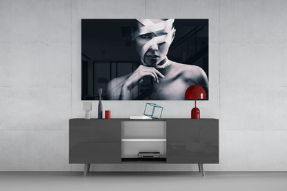 Modern living room with black and white portrait glass art mounted above gray media console with red accent lamp and decorative objects.