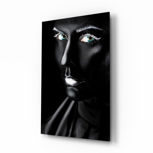 Woman's face with striking turquoise eyes against black background on glass wall art, displayed at angle.