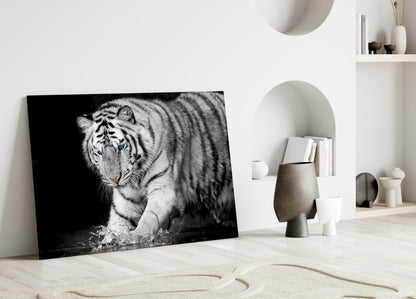 Black and white glass wall art depicting a tiger with blue eyes leaning against a white wall in a minimalist interior setting.