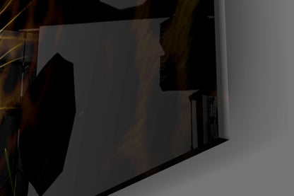 Night photograph of illuminated glass wall art panel mounted on white wall, silhouetted against interior lighting.