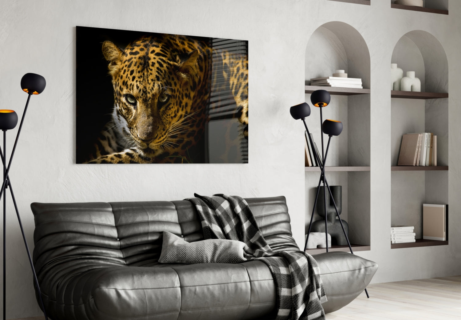 Leopard glass wall art displaying a close-up of a spotted leopard's face against black background, mounted above a gray leather sofa.