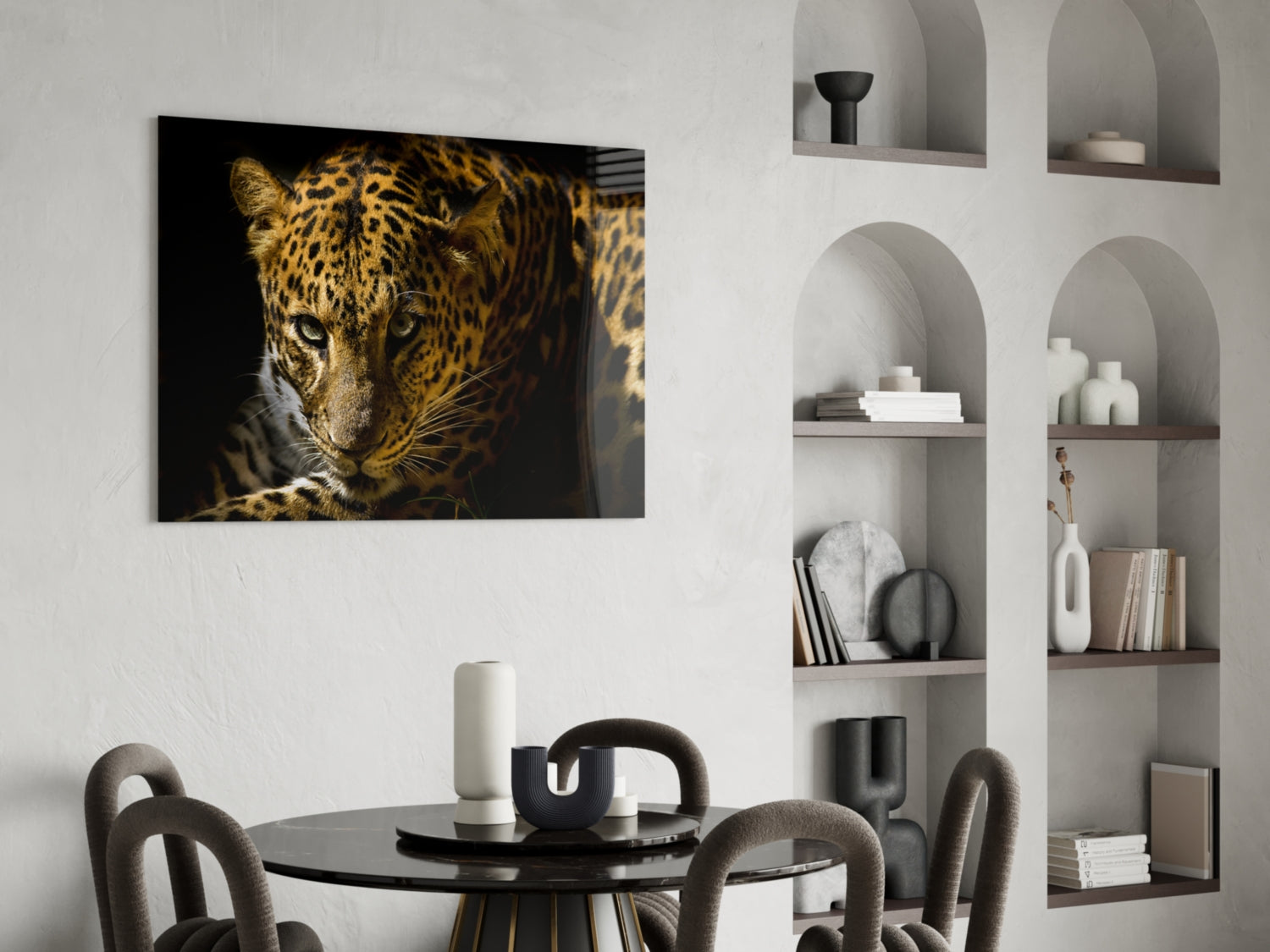 Glass wall art depicting a leopard's face in golden and black tones against dark background, displayed above round dining table in modern interior.