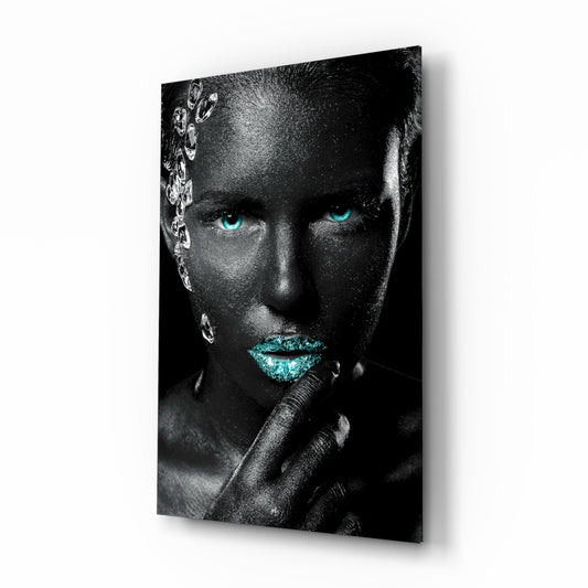 Glass wall art displaying a grayscale portrait with striking turquoise eyes and lips, featuring silver crystalline gems on the left side, mounted at an angle.