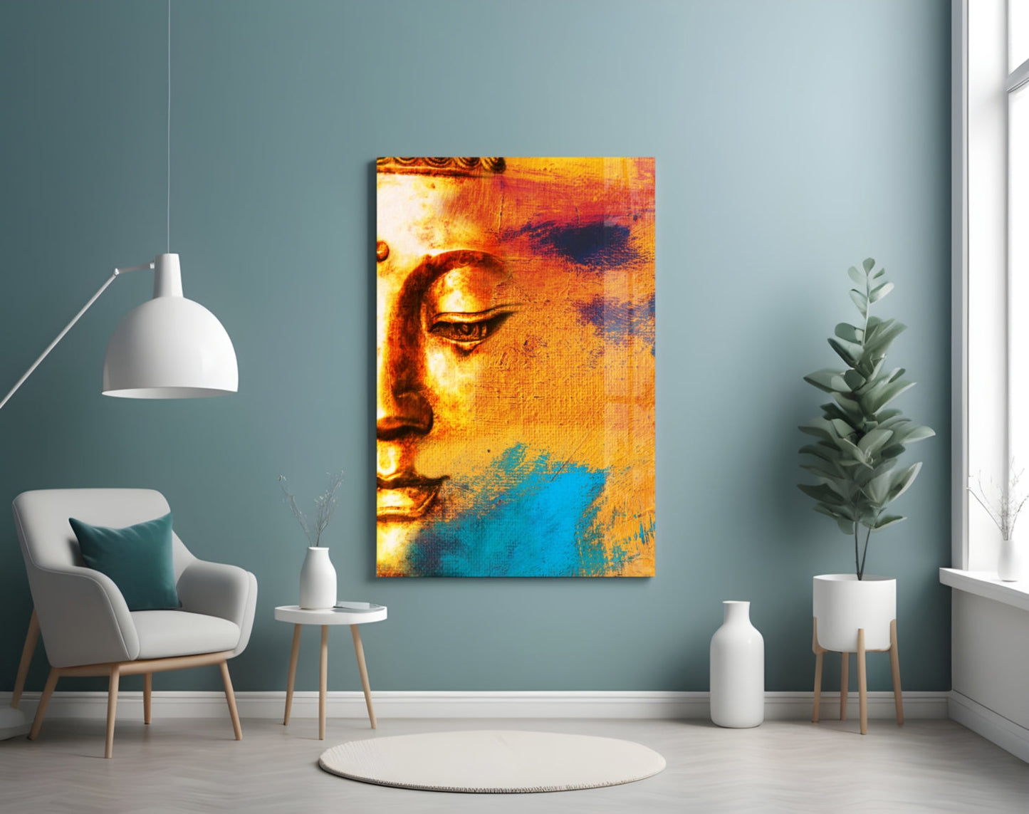 Buddha Portrait Glass Wall Art displayed on muted blue wall above white chair, showing golden and turquoise colored Buddha face.