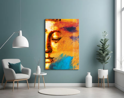 Buddha Portrait Glass Wall Art displayed on muted blue wall above white chair, showing golden and turquoise colored Buddha face.