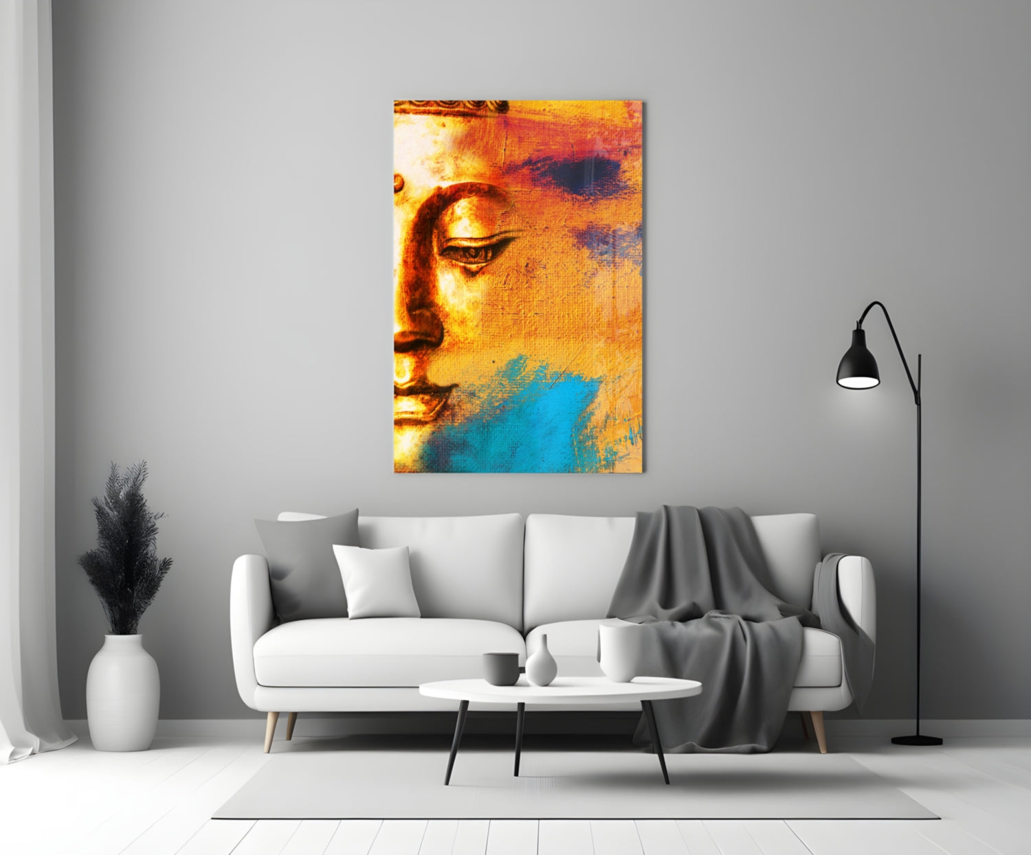 Buddha Portrait Glass Wall Art in warm gold and cool blue tones displayed above a white sofa in a minimalist living room.