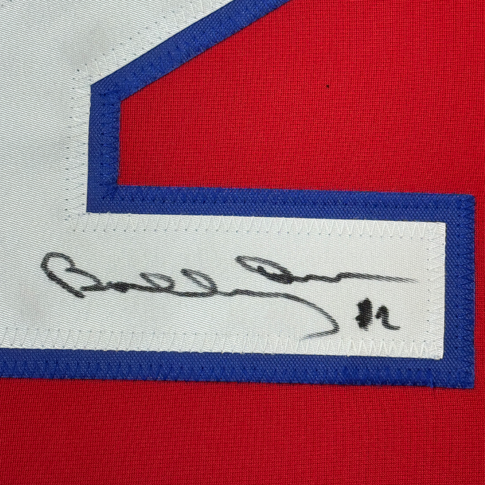 Close-up of handwritten signature on white stripe of red, white, and blue hockey jersey.
