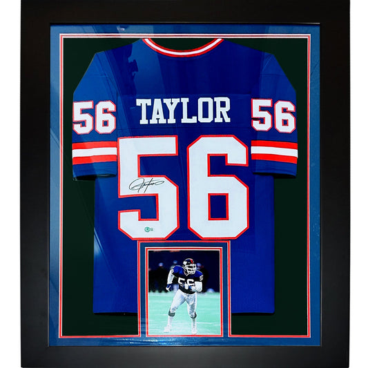 Back view of a framed blue jersey with white 56 and TAYLOR lettering, signed, plus a small photo below.