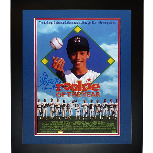 Framed movie poster for "Rookie of the Year" featuring young baseball player in Cubs uniform with autograph, blue matting and black frame.