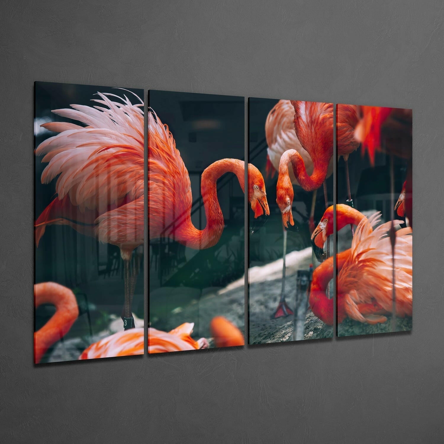 Four-panel glass wall art displaying vibrant red and orange flamingos in shallow water against dark background, mounted on gray wall.