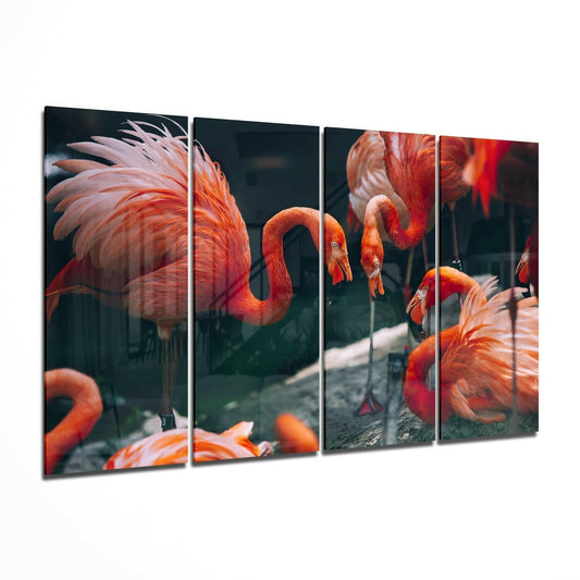 Four-panel glass wall art displaying vibrant orange and red flamingos with curved necks against dark background, shown at angled perspective.
