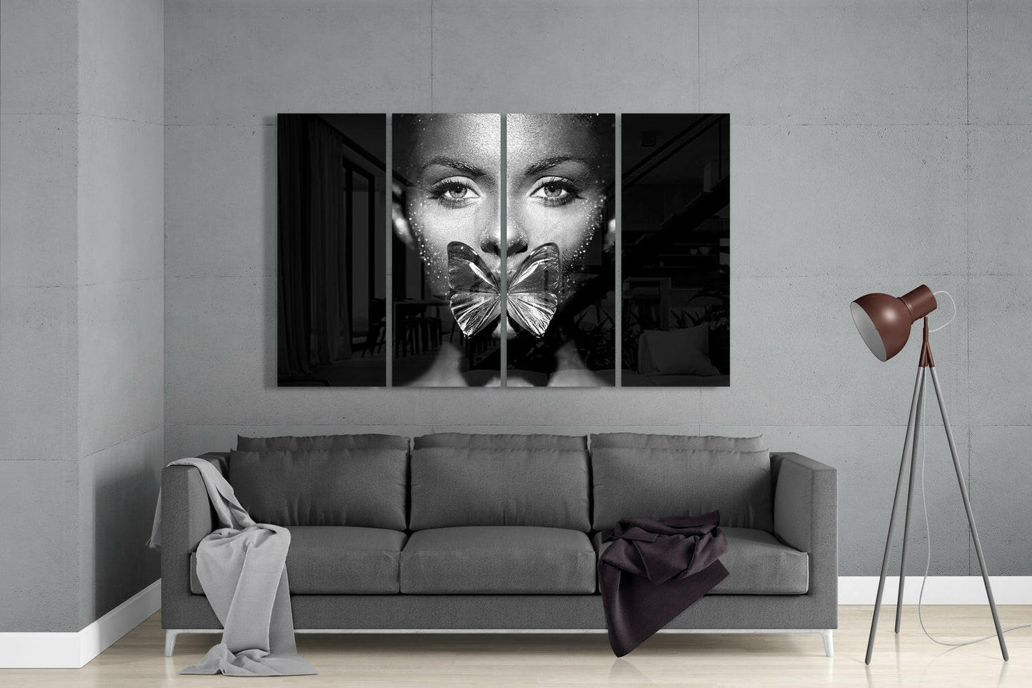 Black and white four-panel glass wall art displaying a woman's face with a butterfly covering her mouth, installed above a gray sofa in a modern living room.