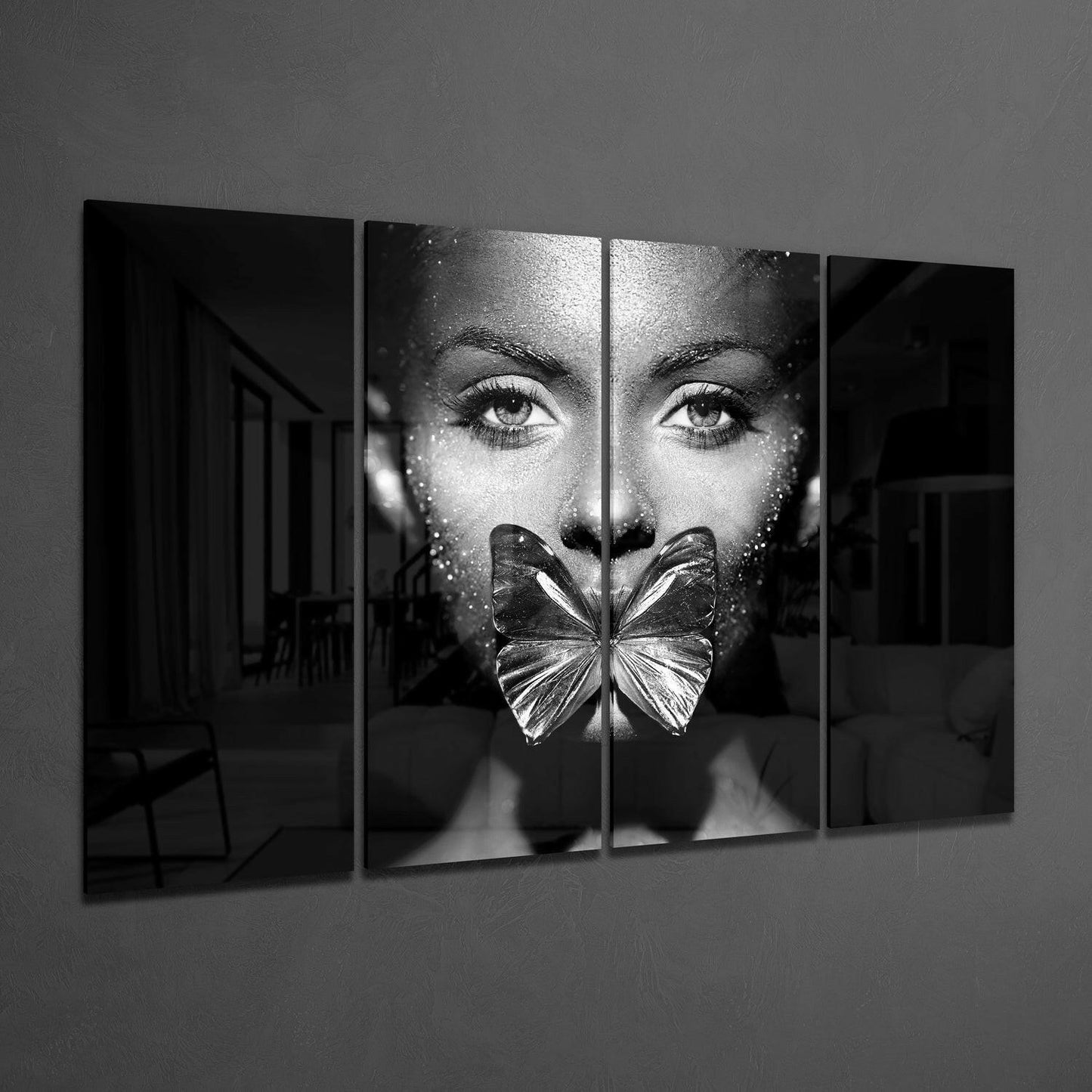 Four-panel black and white glass wall art displaying a woman's face with a butterfly covering her mouth, installed on a gray wall.
