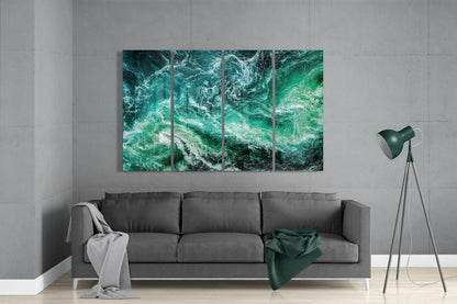 Four-panel turquoise ocean waves glass art hung above gray sofa in modern living room with floor lamp.
