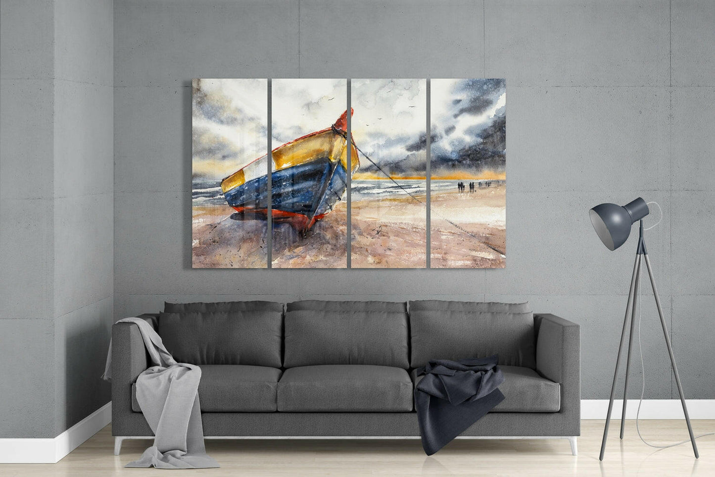 Four-panel glass wall art displaying a weathered fishing boat with yellow and blue hull beached on sand, hung above gray sofa in modern living room.