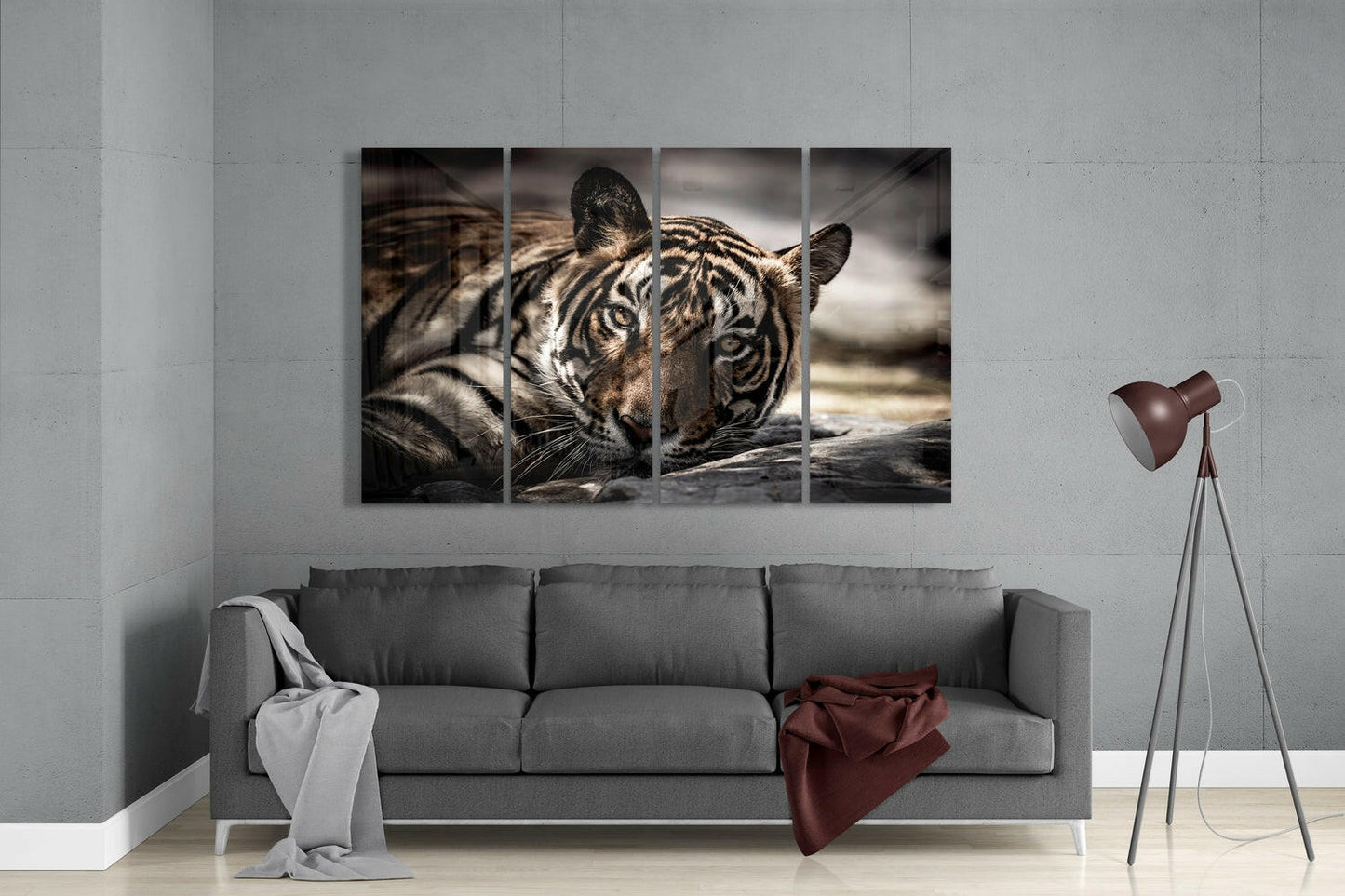 Four-panel glass wall art displaying a close-up tiger face with striped markings, mounted above a gray sofa in a modern living room.