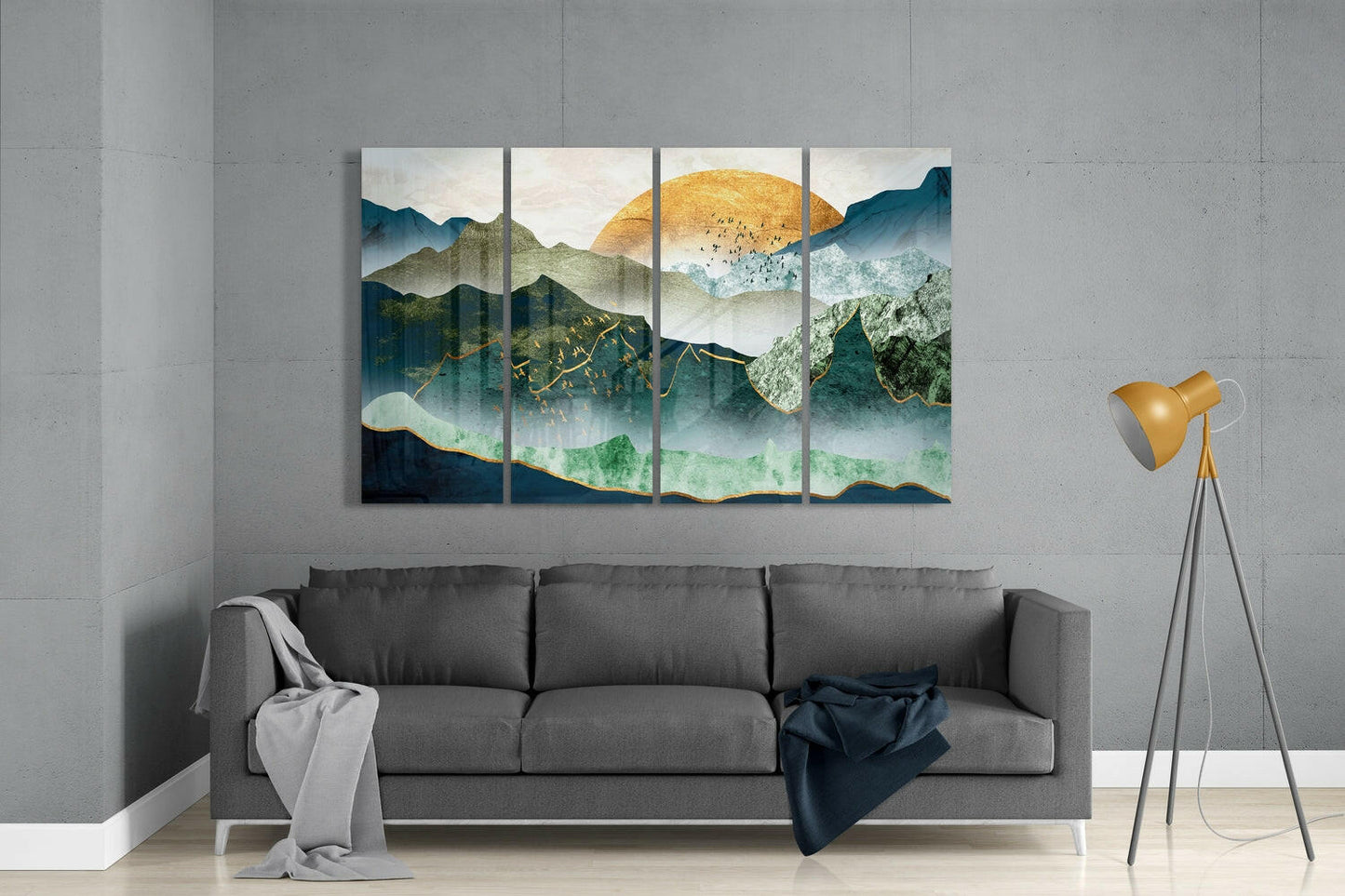 Four-panel glass wall art depicting layered mountains with golden sun and green mist, displayed above gray sofa in modern living room.
