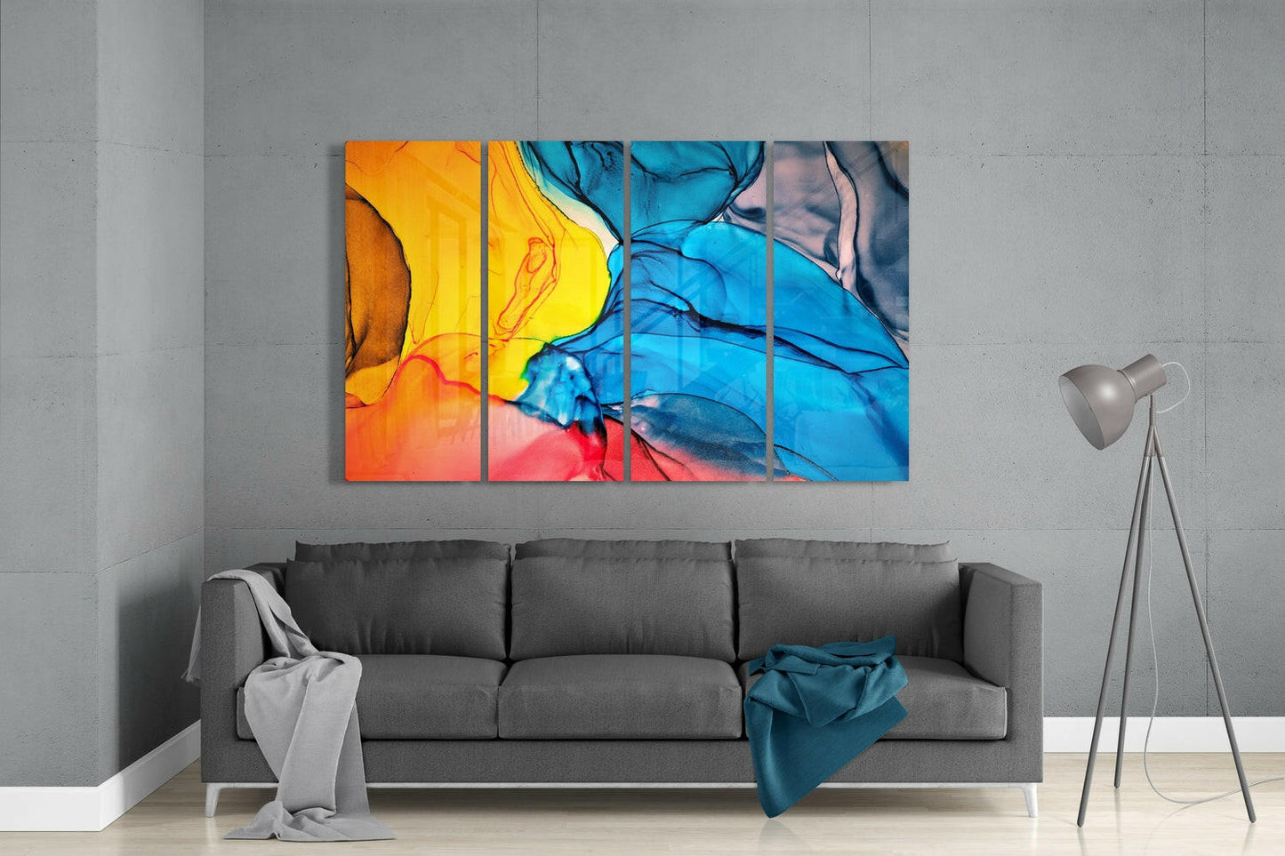 Colorful abstract glass wall art panel displayed above gray sofa in minimalist interior setting with tripod lamp.