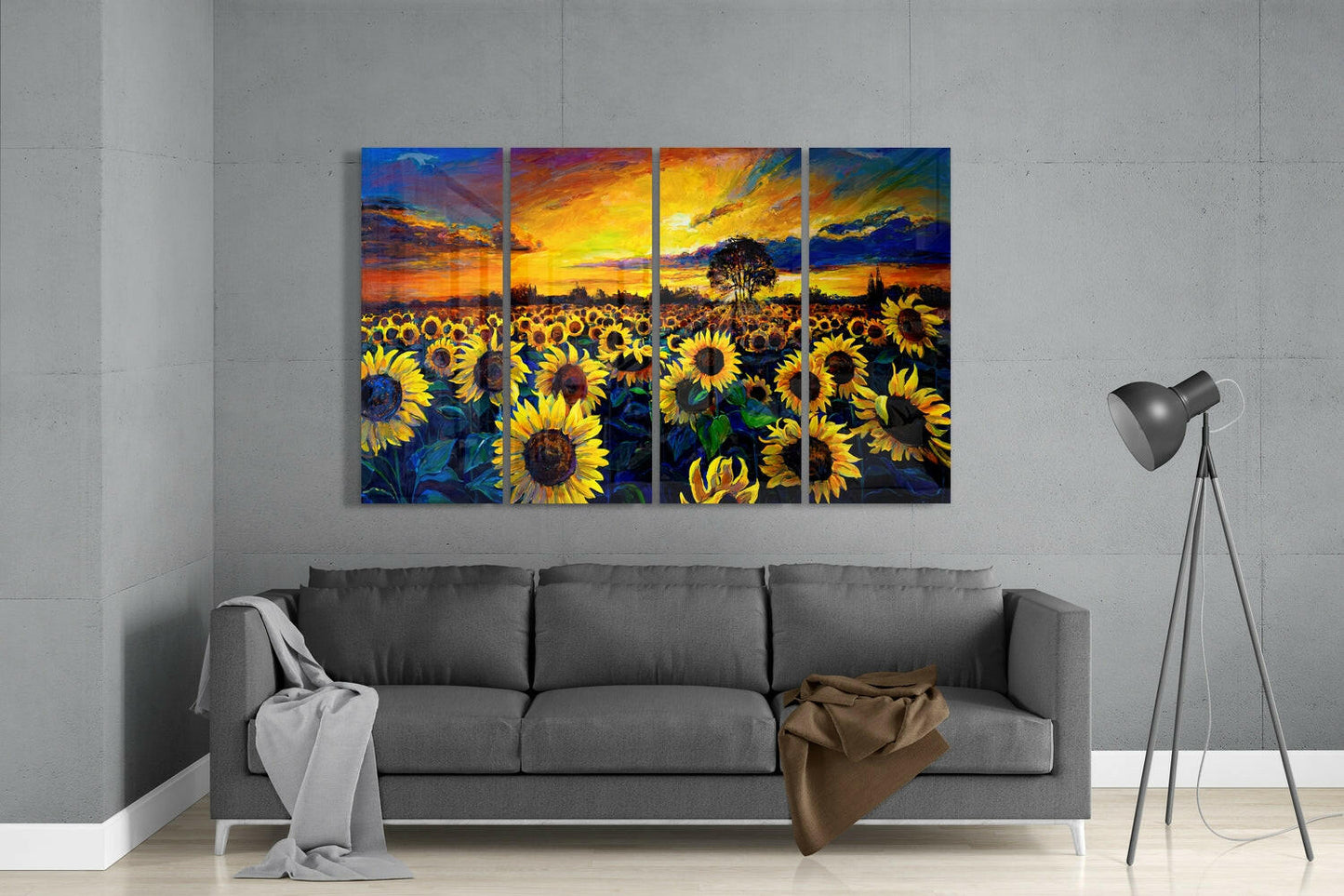 Four-panel glass wall art depicting a vibrant sunflower field at sunset, hung above a gray sofa in a modern living room.