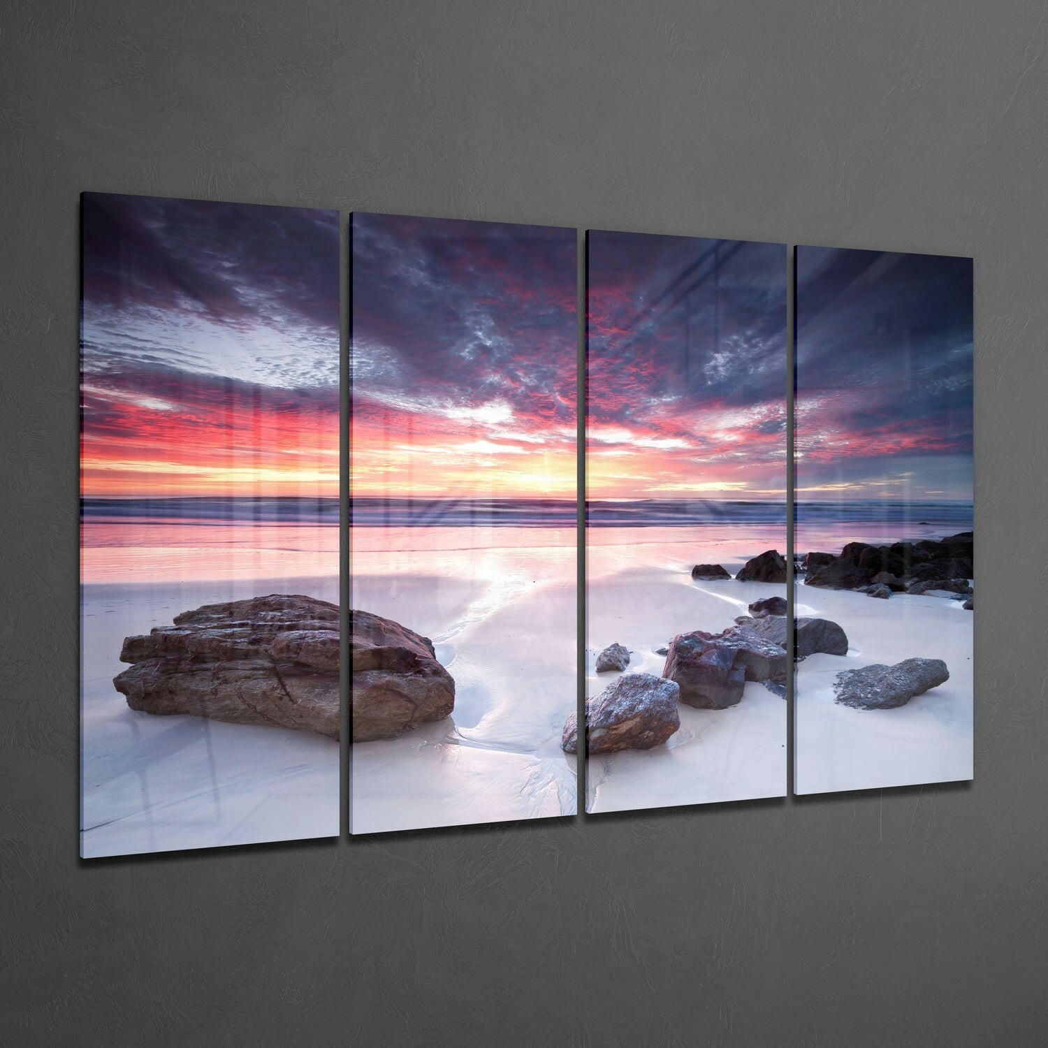 Four glass panels displaying a coastal sunset scene with pink and orange sky, rocky outcrops, and smooth water, mounted on gray wall.