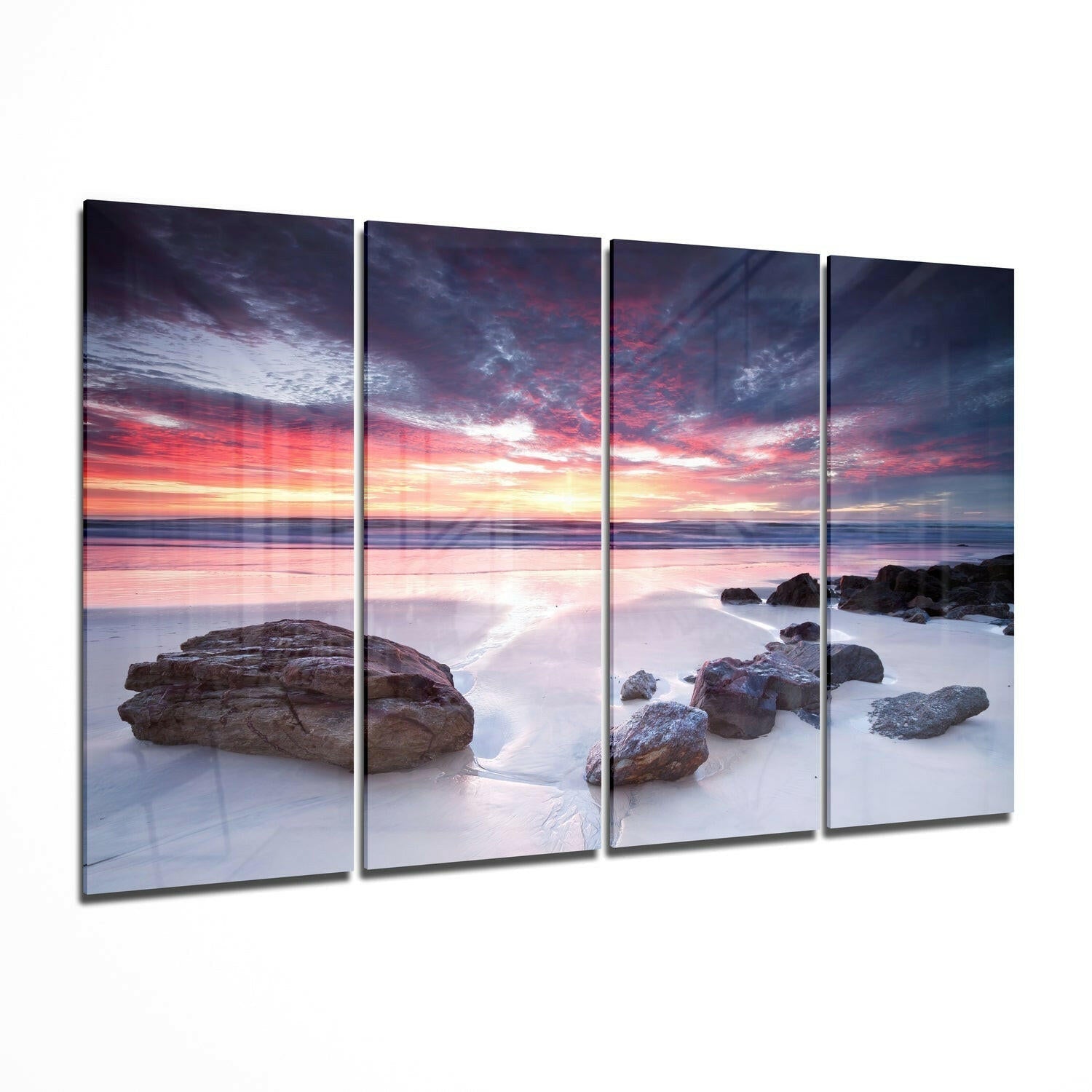Four-panel glass wall art depicting a rocky beach at sunset with pink and orange sky reflecting on wet sand and shallow water.