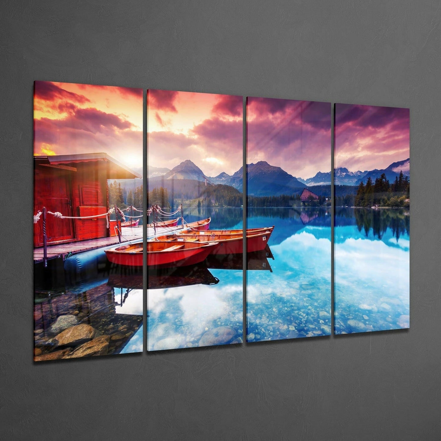 Four-panel glass wall art displaying red boats on a pristine alpine lake at sunset with mountains and dramatic sky.