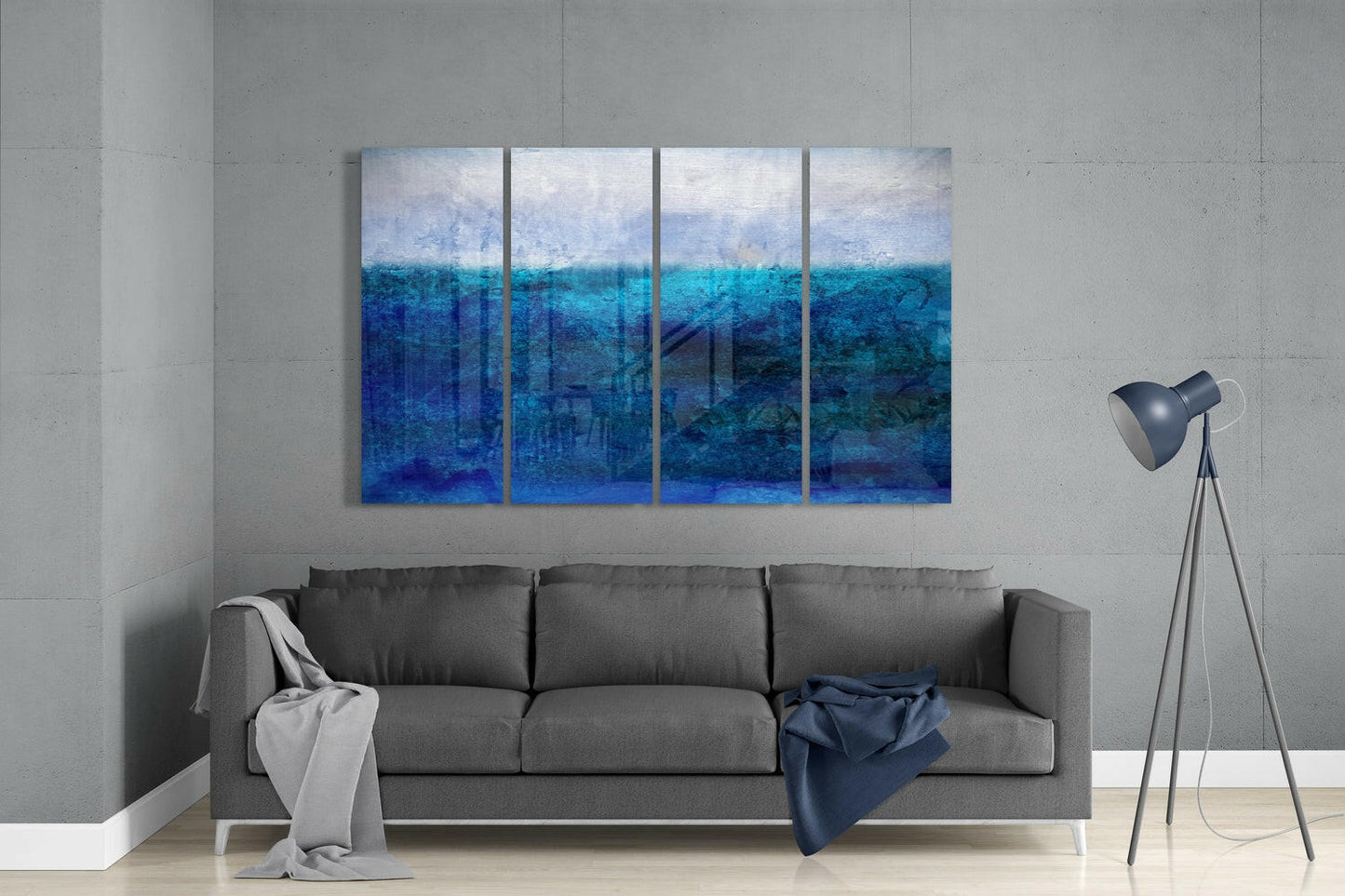 Four-panel blue ocean gradient glass wall art hanging above gray sofa in minimalist living room interior.