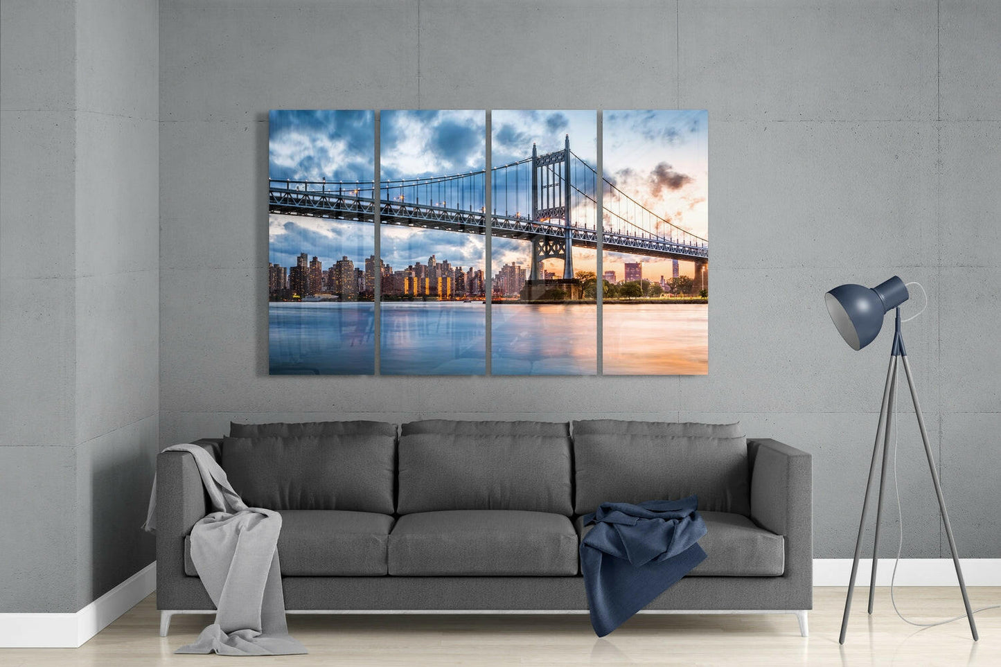 Four-panel glass wall art displaying Manhattan bridge and skyline at sunset, hung above gray sofa in modern living room interior.
