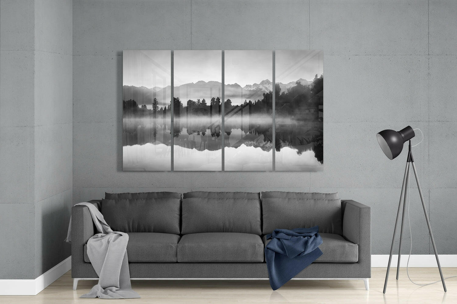 Four-panel black and white glass wall art depicting misty mountains and forest reflected in still water, displayed above gray sofa in modern living room.