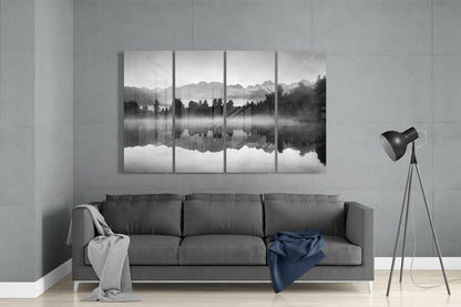 Four-panel black and white glass wall art depicting misty mountains and forest reflected in still water, displayed above gray sofa in modern living room.