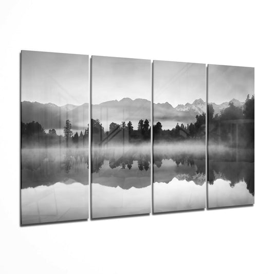 Four-panel black and white glass wall art displaying a misty mountain lake landscape with forested shoreline and mirror reflections.