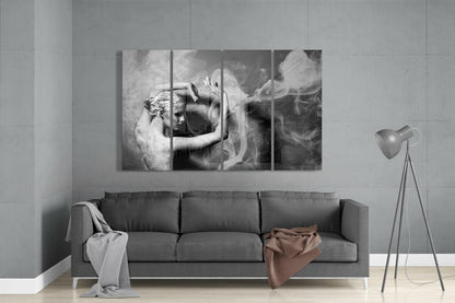 Black and white four-panel glass wall art above gray sofa showing woman with flowing smoke in minimalist interior setting.