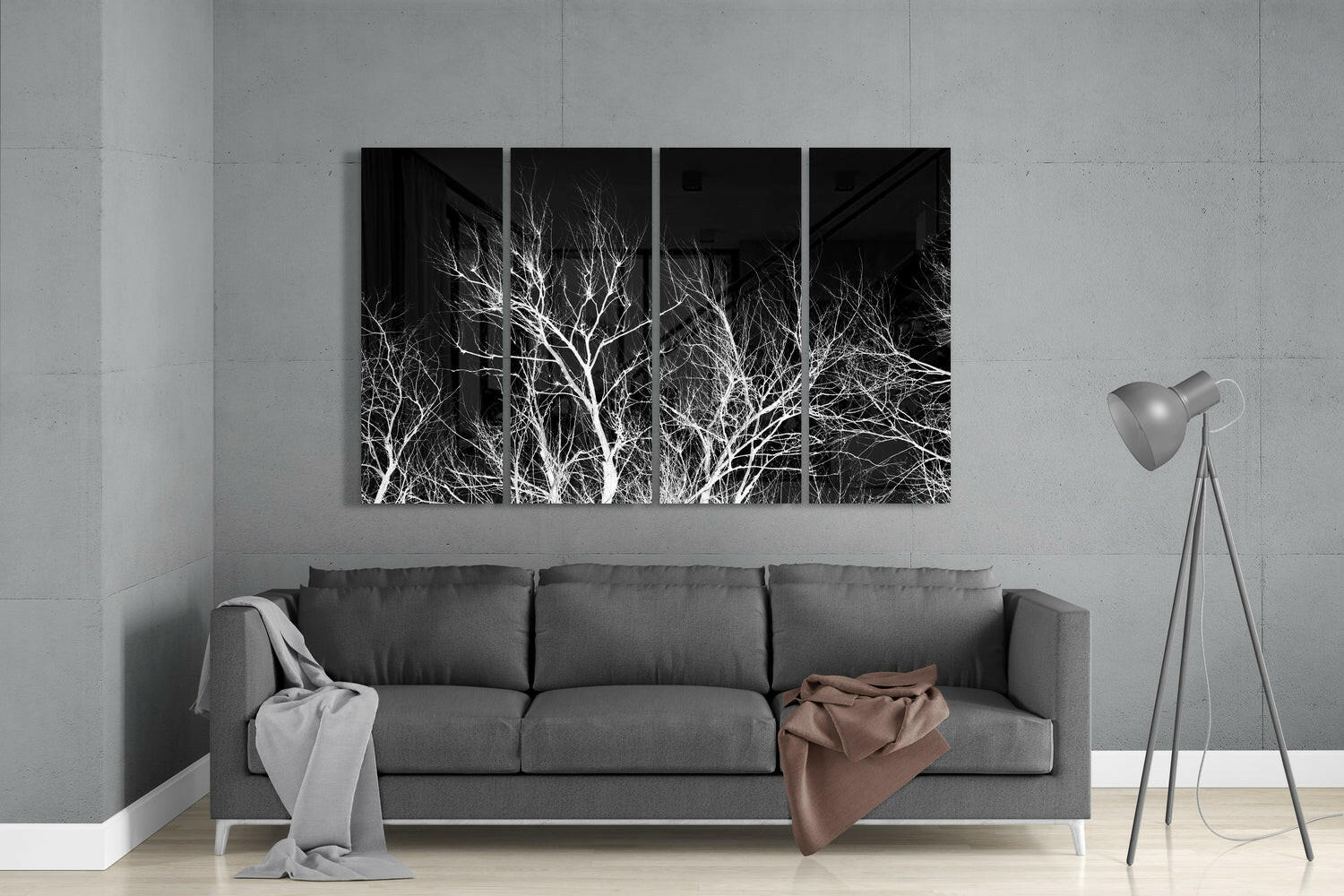 Modern living room with gray sofa displaying four-panel black and white bare tree branches wall art above, floor lamp beside.