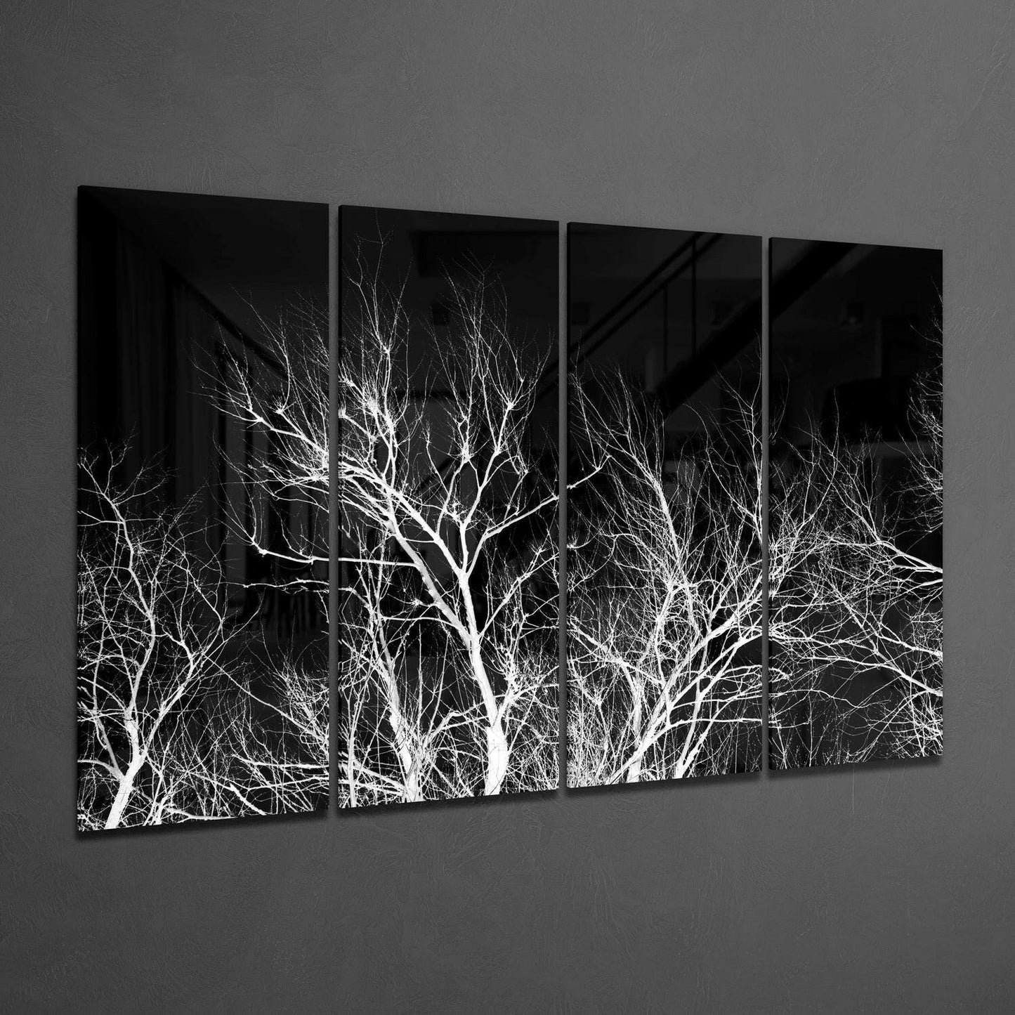 Four black glass panels displaying white bare tree branches against dark background, hung on gray wall at angle.
