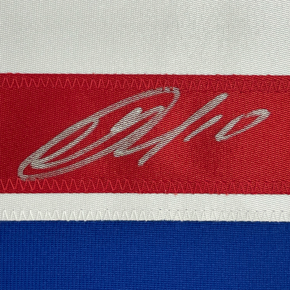 Close-up of embroidered signature on red stripe of hockey jersey with white and blue stripes visible.