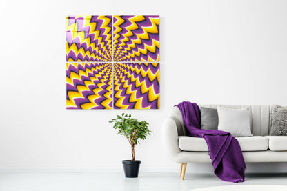 Yellow and purple radiating zigzag pattern glass art displayed above potted plant and white sofa with purple throw blanket.