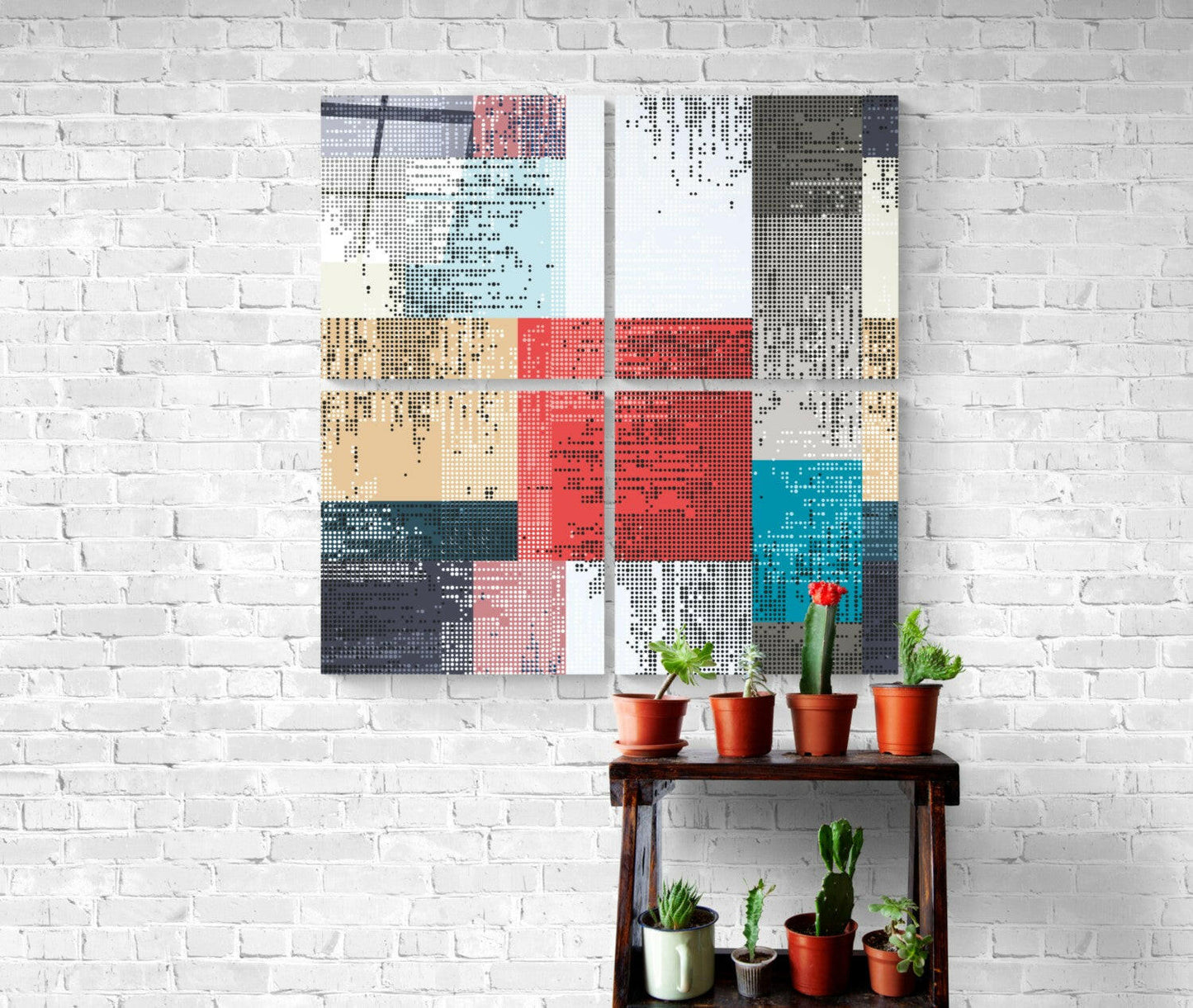 Dots Quadro glass wall art in red, blue, tan, and gray displayed above wooden shelf holding potted cacti against white brick wall.